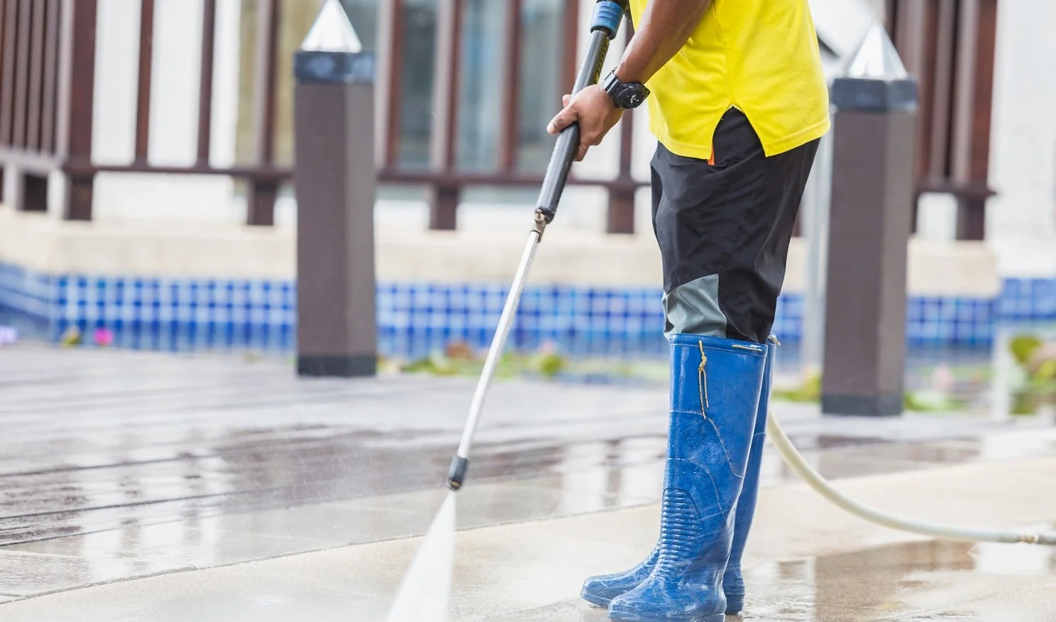 Worker pressure washing a wooden deck and outdoor living area